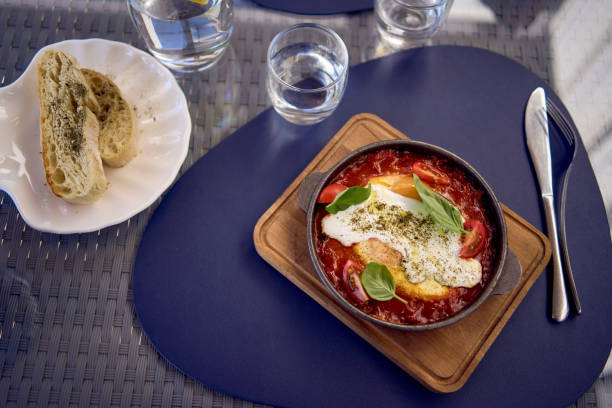 medium sized woman in peach color dress eating Shakshouka in modern restaurant