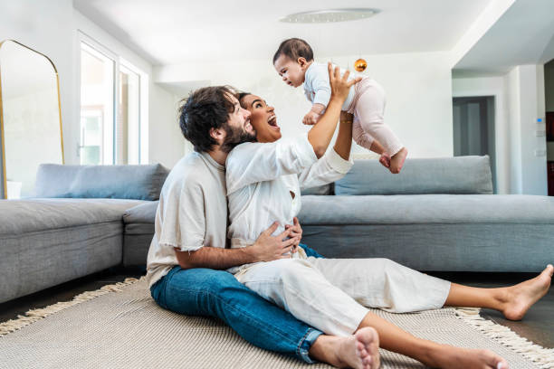Multiracial husband and wife playing with cute little daughter at home -Cheerful parents embracing beautiful baby children indoors - Family life style concept Multiracial husband and wife playing with cute little daughter at home -Cheerful parents embracing beautiful baby children indoors - Family life style concept mum new boyfriend stock pictures, royalty-free photos & images