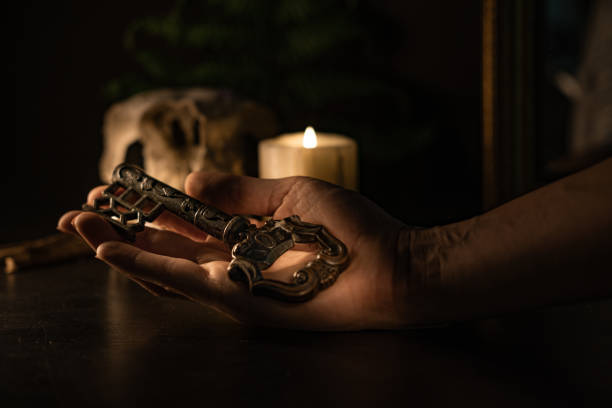 A woman holds an antique key, a candle burns in the background. Dark atmosphere.