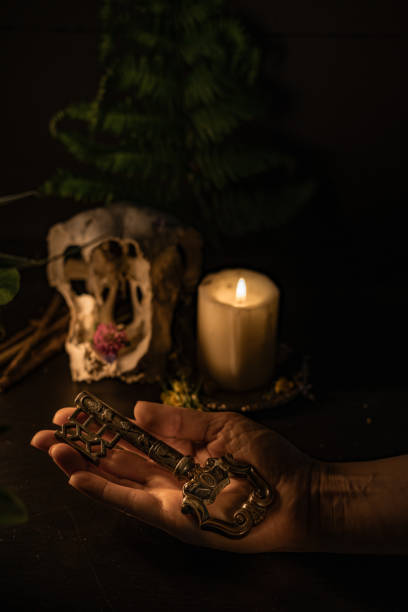 A woman holds an antique key, a candle burns in the background. Dark atmosphere.