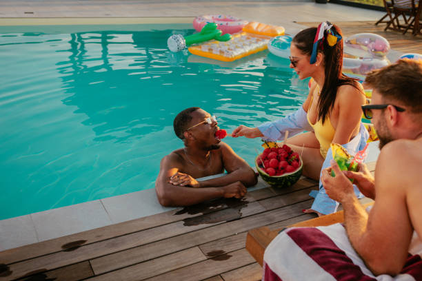 istock Girl feeding a boy fruit while they chill in the pool 2152894332