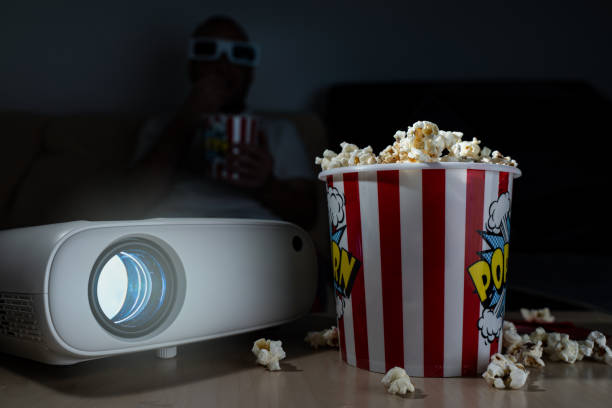 istock man watching movie with a projector at home while eating popcorn 2152894335
