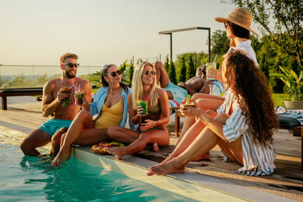 istock Friend group sitting by the pool, drinking cocktails and having fun 2152894338