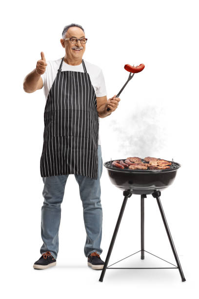 istock Mature man baking meat on a barbecue grill and holding a sausage with a fork 2152899656