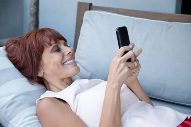 istock Happy woman texting with mobile phone lying in the sofa 2152910348