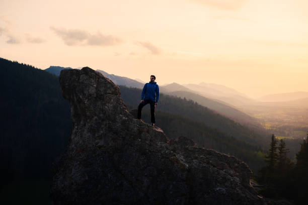 istock Man on rock in mountains at sunset, with clouds and sky in background 2152917571