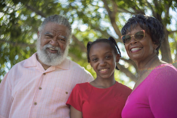 Grandparents with their granddaughter outdoors happy and together.