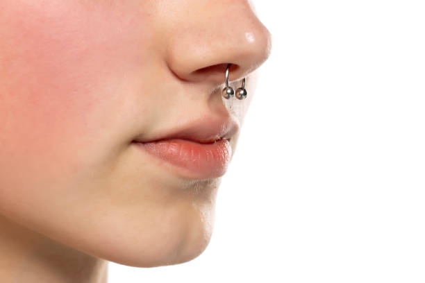Closeup of a young serious woman's visage with piercing septum hanging from her nose Closeup of a young serious woman's visage with piercing septum hanging from her nose. septum stock pictures, royalty-free photos & images