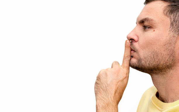 istock Stop talking gesture. Shushing or shh. Man holds his index finger on his lips. 2152917937