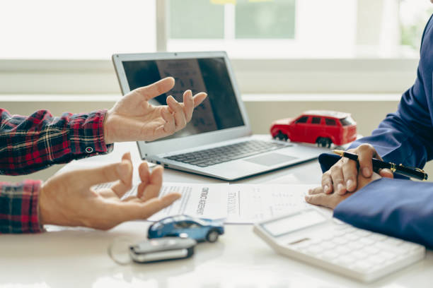 istock A close-up image of a salesperson introducing a customer sitting at a table with a small car and car keys. car dealer sales And the new owner has entered into a contract to sell and lease cars. 2152918662