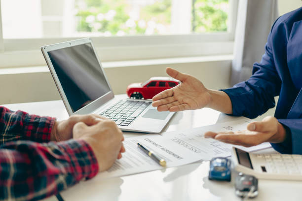 istock A close-up image of a salesperson introducing a customer sitting at a table with a small car and car keys. car dealer sales And the new owner has entered into a contract to sell and lease cars. 2152918664