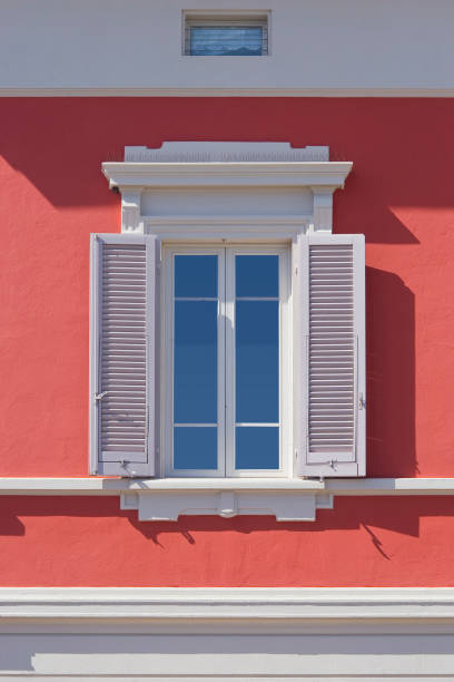 istock Old neoclassical italian facade with window and wooden shutter against a red colored plaster wall 2152918821