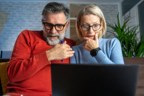 istock Serious couple sitting on couch in new home checking bills 2152919360