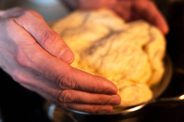 Professional baker passionately kneading dough in a restaurant kitchen, with a closeup and blurred motion to capture the dynamic movement and expertise. The image showcases the art of bread making.