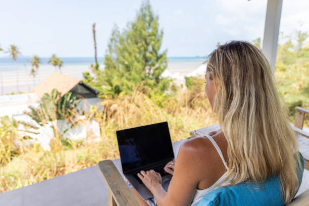 istock Woman Working on Laptop Overlooking Tropical Seaside 2152921759