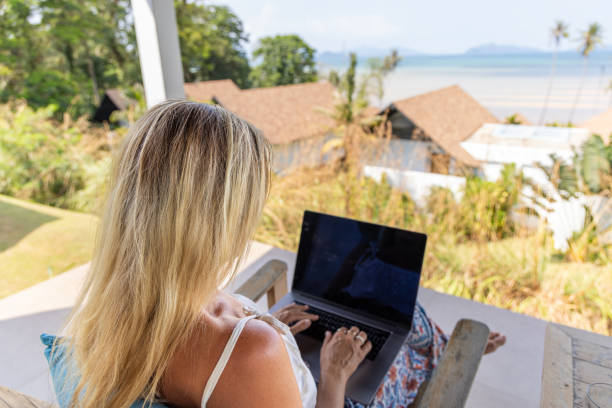 istock Woman Working on Laptop Overlooking Tropical Beach 2152921783