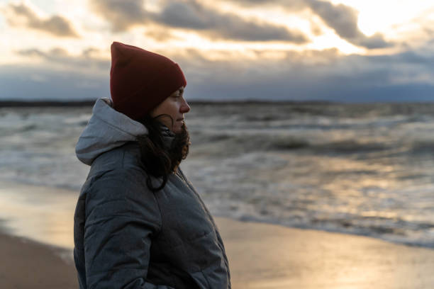 istock a woman stands on the seashore in the cold during a storm. 2152922033