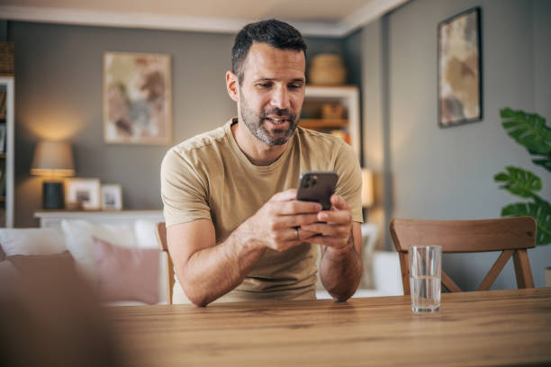 istock A man sits at a wooden table and uses a smart phone 2152928487