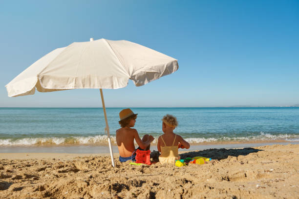 istock Little boy and girl sitting on beach 2152929708