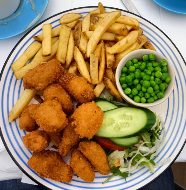 bowl with bread and plate with cutlet french fries and vegetables on a wooden background