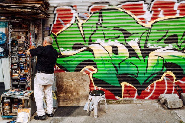 Editorial image of a man working at an open shopfront with a colorful graffiti mural in Istanbul, Turkey on June 6, 2022.