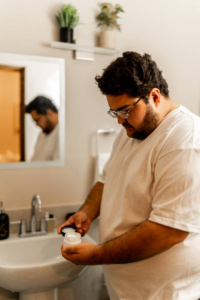 istock Young man holding face cream at bathroom 2152937791