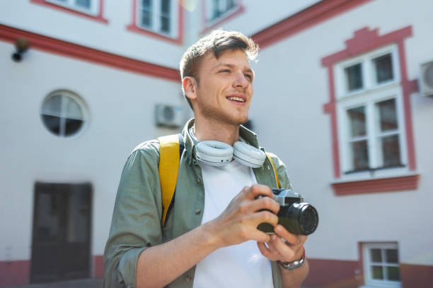 Creative photographer tourist holding retro camera taking photos in city