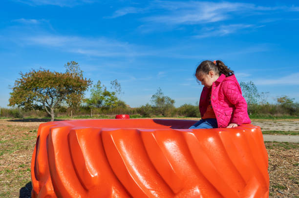 young girl playing on a brightly colored tractor wheel at a farm fair on Halloween