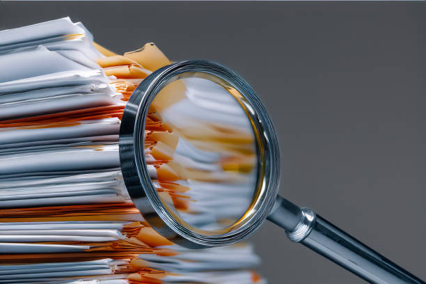 Pile of binders partially obscured by a magnifying glass