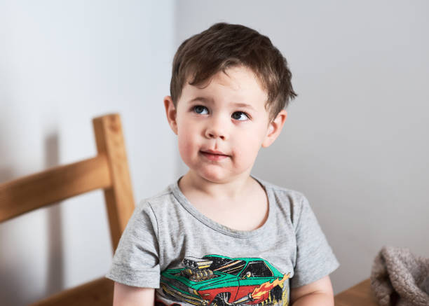 Three-year-old boy sitting on the bed in his room