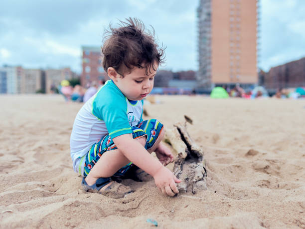 pretty young toddler boy is playing on the beach