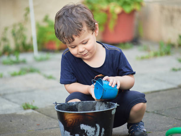 istock cute toddler playing with water in the backyard 2152944411