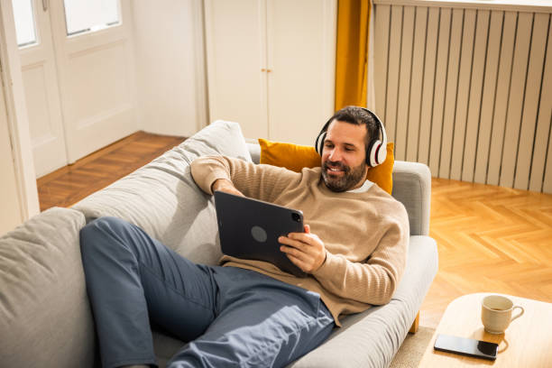 istock Man lying on sofa at home and watching movie on digital tablet 2152945731