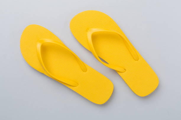 istock Bright yellow flip-flops on color background, top view. Summer concept 2152949082