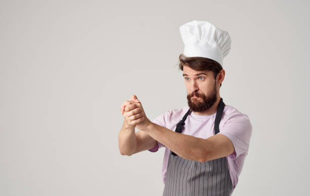 A cook in a headdress is gesturing with his hands on a light background, success emotions
