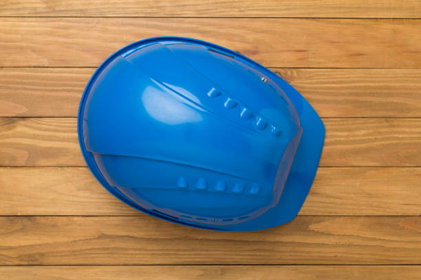 Blue construction helmet on wooden background, top view