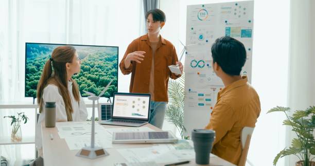 istock Diverse team meeting focus on environmental strategy, using models of wind turbines and solar panels to discuss renewable energy solutions. Eco-Friendly Business Team Discussing ESG Goals. 2152953021