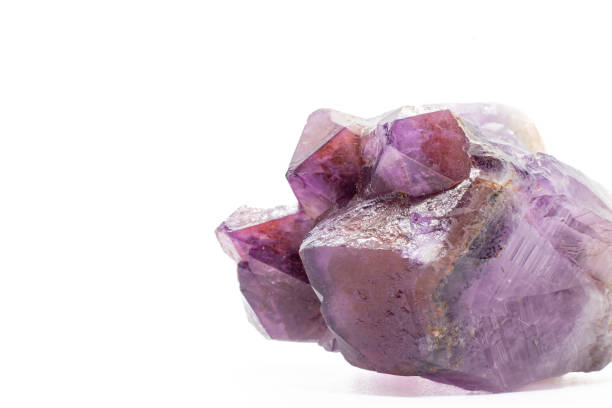 Purple and red amethyst crystal natural point cluster, purple quartz crystal amethyst with iron and hematite inclusions isolated on a white surface background close up macro
