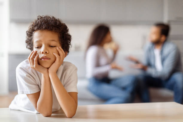 Little Boy Sitting at Table With Hands on Face