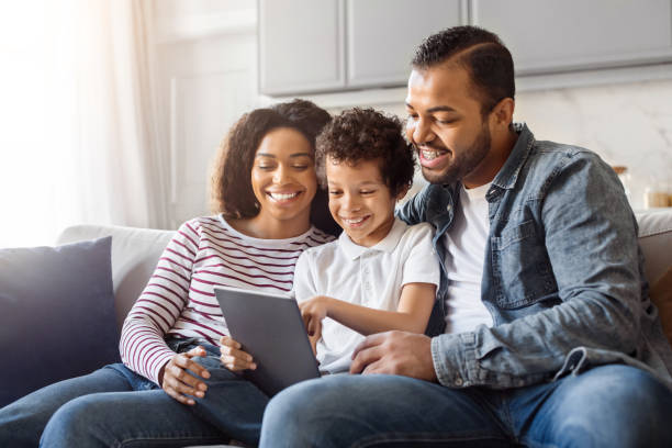 istock African American Family Sitting on Couch Using Tablet 2152962673