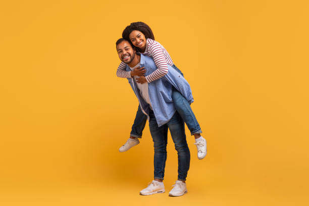 istock Delighted young black couple having fun together against yellow background in studio 2152963649