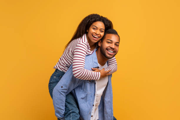 istock Happy laughing young black couple having fun against yellow studio background 2152963661