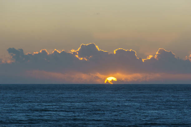 Calm sea with waves and sunset at moody cloudy sky