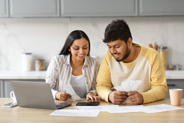 istock Smiling indian couple holding papers, calculating domestic bills, kitchen interior 2152965925
