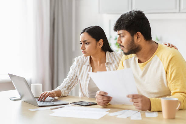 istock Serious Indian couple discussing finances online, kitchen interior 2152965944
