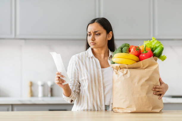 istock Worried Indian woman with groceries analyzing receipt 2152965955