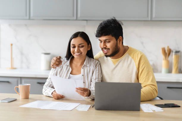 istock Happy young indian spouses reading letter from bank, kitchen interior 2152965990