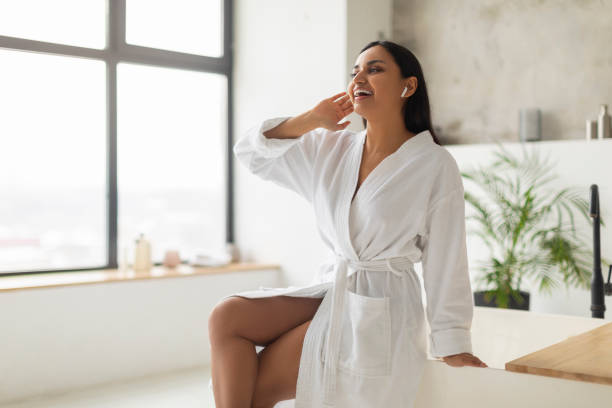 istock Young indian woman in bathrobe singing while filling bathtub 2152967320