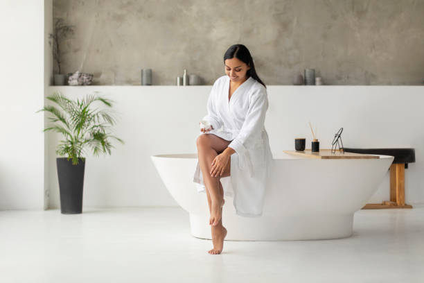 istock Eastern Woman In Bathrobe Moisturizing Smooth Legs With Moisturizer 2152967356