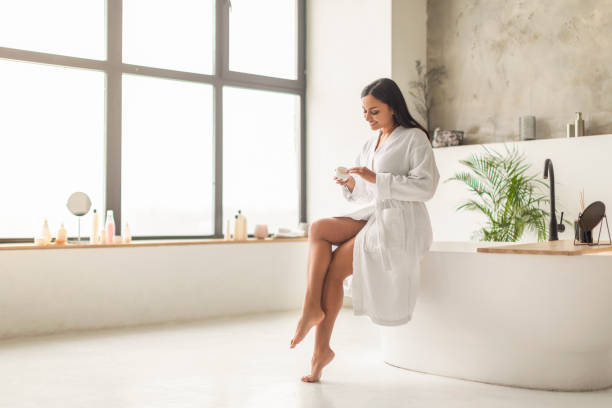 istock Attractive indian woman sitting on bath, applying body cream 2152967378
